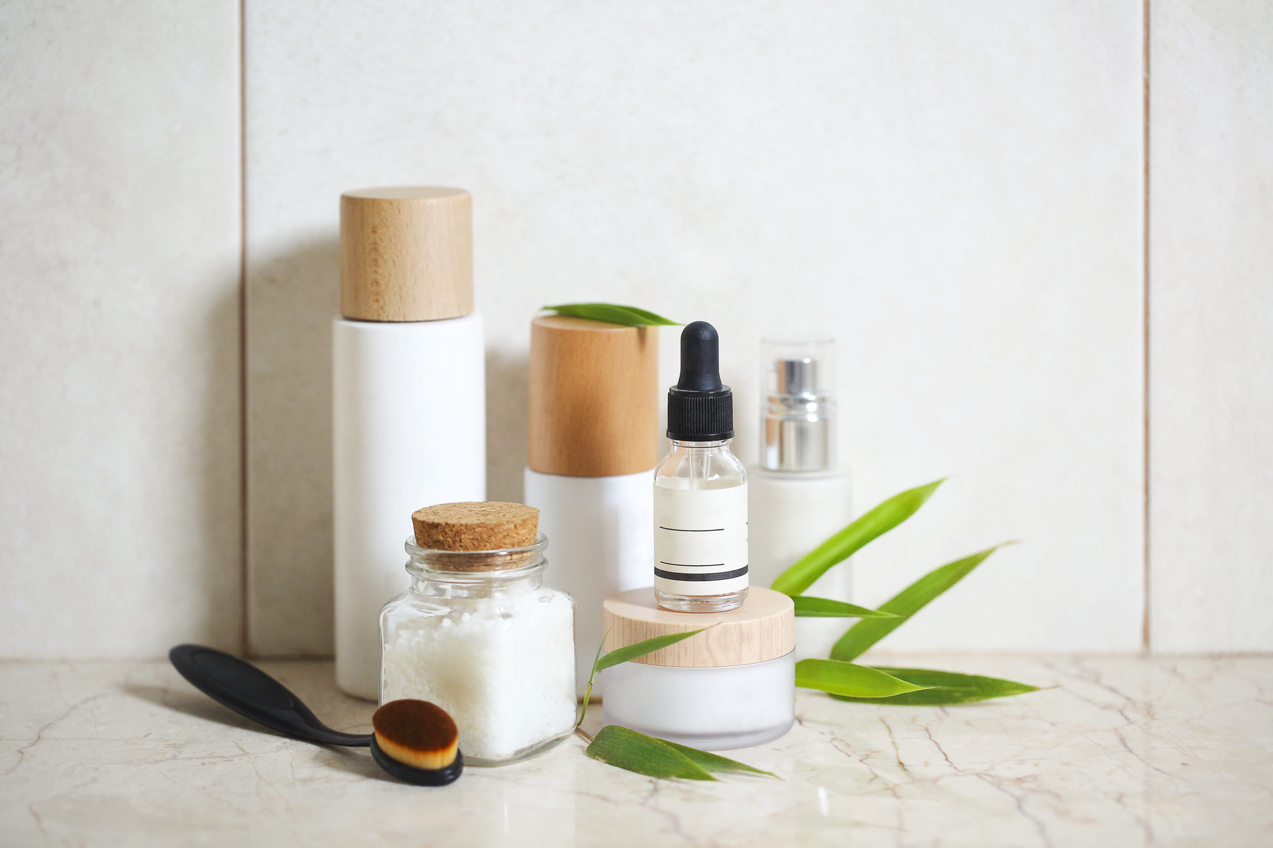 Face cream, serum, lotion, moisturizer and sea salt among bamboo leaves